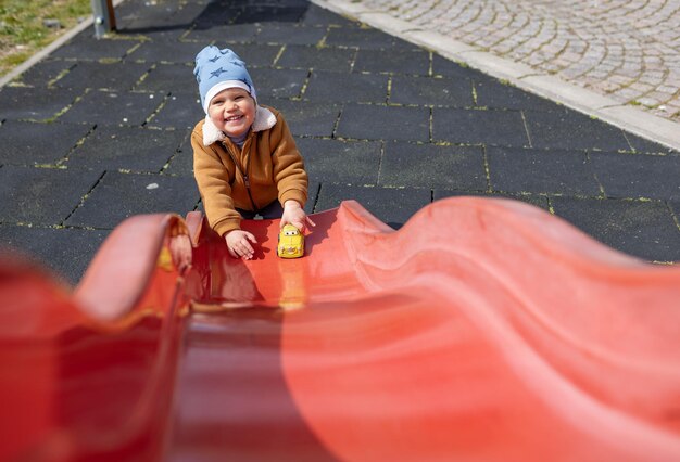 A boy rides his car on a hill in autumn weather