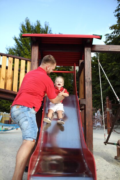 Boy rides on a wooden slide with his family