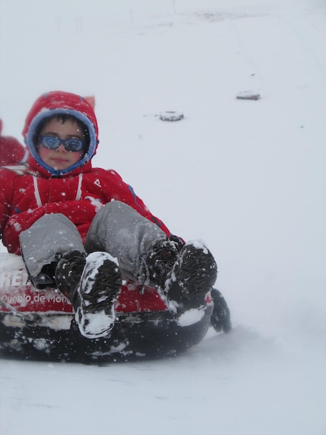 雪に覆われた畑の上でインフレータブルに乗っている少年