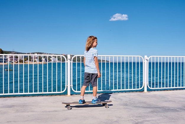 Boy riding a longboard on a pier at sunny day