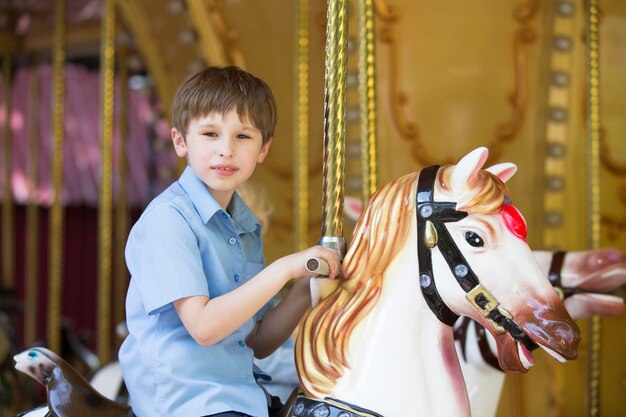 馬の形をしたレトロな回転木馬に乗る少年