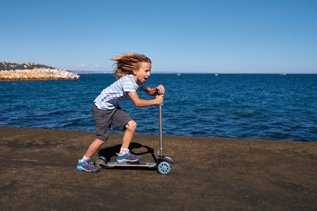 Boy riding a scooter on a pier at sunny day