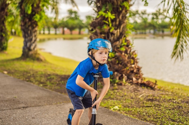 Ragazzo in sella a scooter all'aperto nell'estate del parco i bambini sono felici di giocare all'aperto