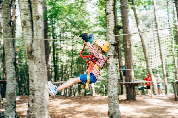 Boy riding a zip line holding on to the safety belt with his hands