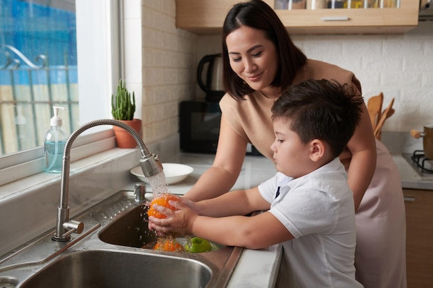 Boy Rinsing Fruits under Tap Water