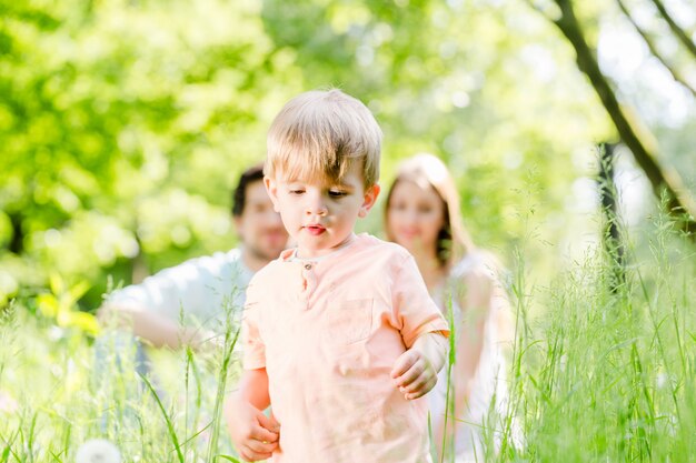 Boy running and playing on meadow with the family