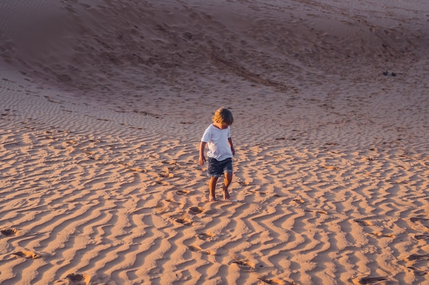 The boy runs around the red desert at dawn. Traveling in a fuss with children concept