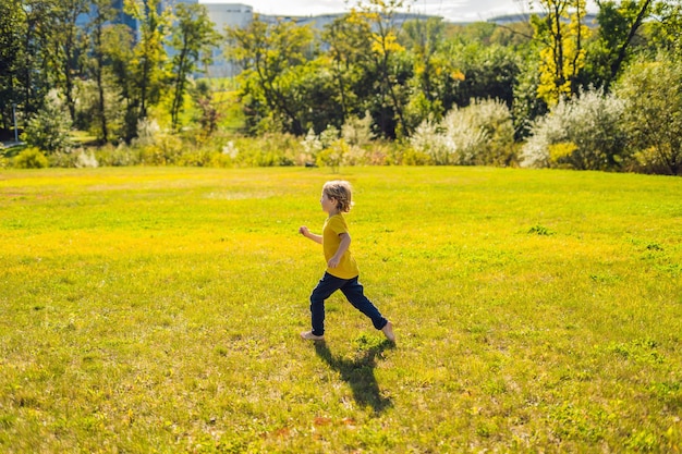 The boy runs in the park on the grass