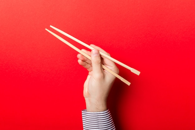 Photo boy's hand showing chopsticks on red