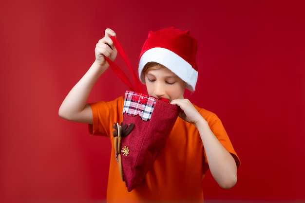 산타의 크리스마스 모자를 쓴 소년이 선물 가방을 들여다보고 있다