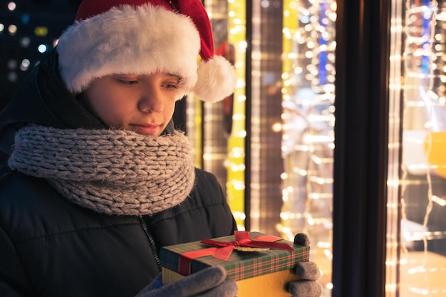 Мальчик в шляпе Деды Морозы с подарочной коробкой ищет и мечтает