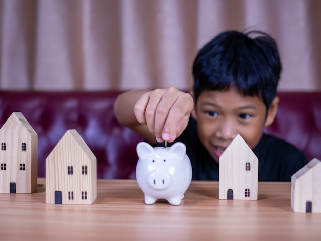 Boy saving money in a white pig piggy bank.Saving concept. Saving for the future.