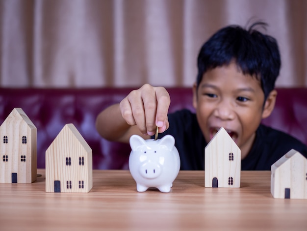 Boy saving money in a white pig piggy bank.Saving concept. Saving for the future.