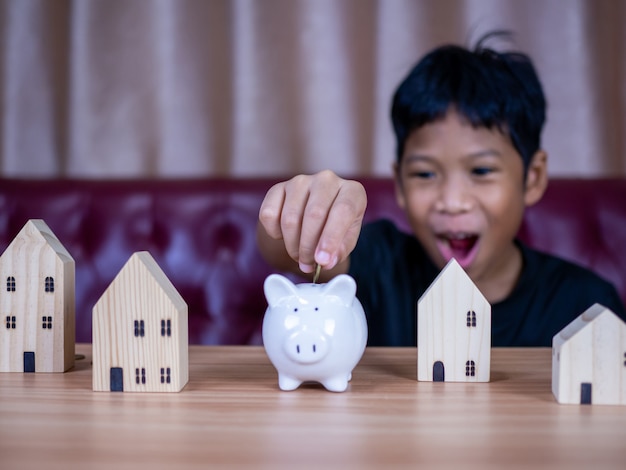Boy saving money in a white pig piggy bank.Saving concept. Saving for the future.