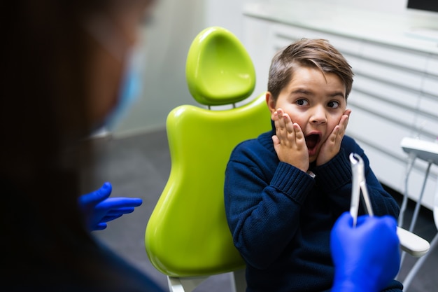 Boy scared of dentist with forceps.