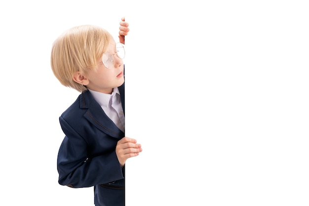 Boy in school uniform peeks out Portrait of schoolboy in isolation white backgroundPlace for your text Copy space