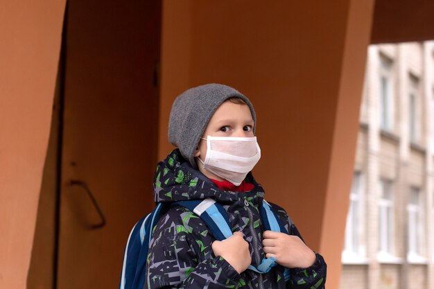 Boy schoolboy walks out of school wearing protective mask