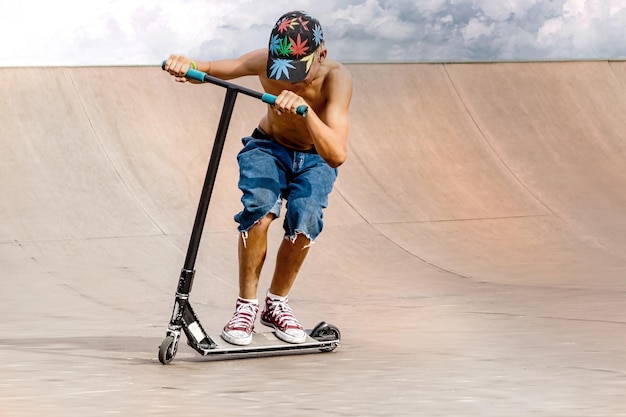 A boy on a scooter and in a skate park makes incredible jumps and tricks Extreme jumping on a scooter The concept of a healthy lifestyle and sports leisure