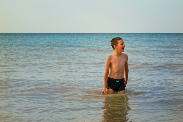 Foto ragazzo in mare. un bambino gioioso esce dal mare.