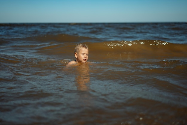 Мальчик в море учится плавать