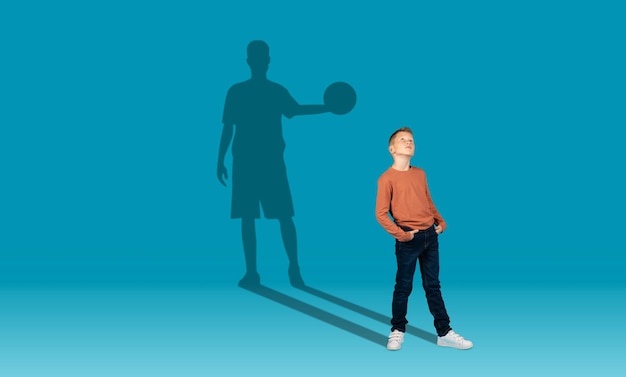 Photo boy and shadow of sportive male basketball player on wall