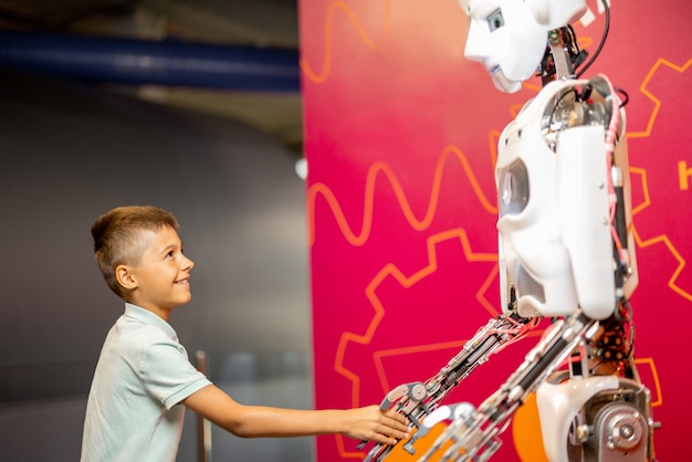 博物館で人型ロボットと握手する少年