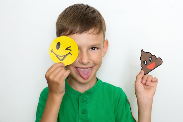 The boy shows emotions and holds funny smiles made of paper