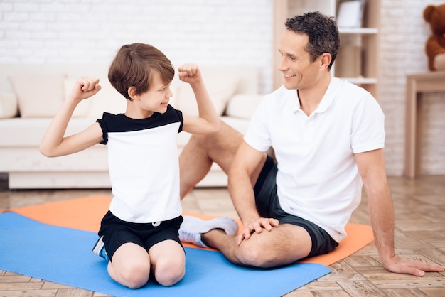 Мальчик показывает свои мышцы своему отцу.