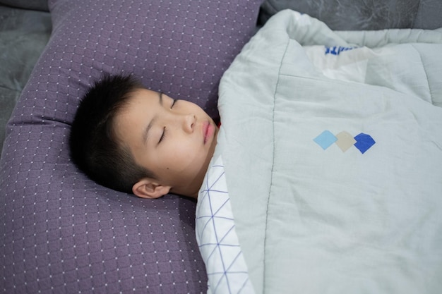 男の子の病気の子供は病気の子供がベッドで寝ている熱を持っています