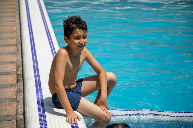 a boy in a side of a swimming pool sitting