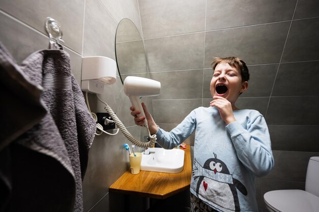 Boy singing with a hair dryer at bathroom