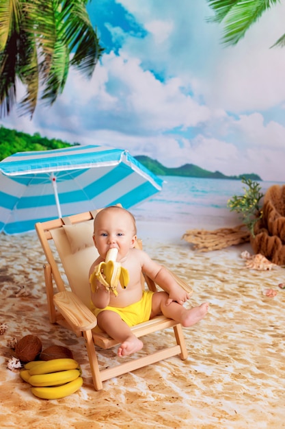 boy sits on a deck chair, sunbathes on a sandy beach with palm trees by the sea and eats a banana