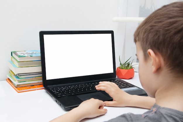 boy sits at a desk with a laptop. Online Home Learning Concept.