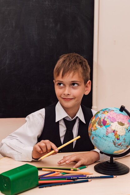 A boy sits at a school desk at a geography lesson