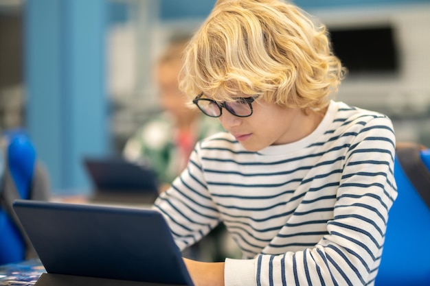 Boy sitting attentively looking at the tablet