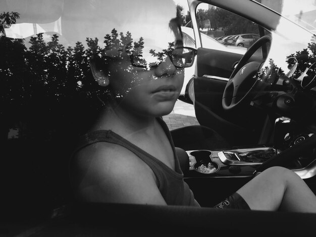 Boy sitting in car seen through window