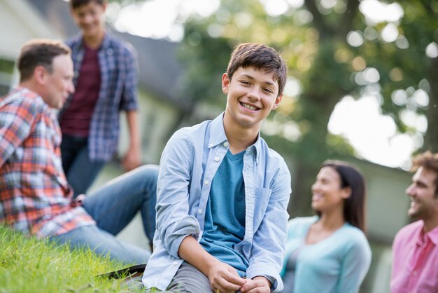 A boy sitting on the grass at a summer party