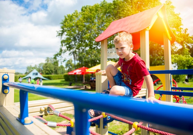 Photo boy sitting on jungle gym at playground