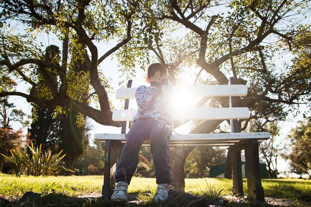 写真 公園のベンチに座っている少年