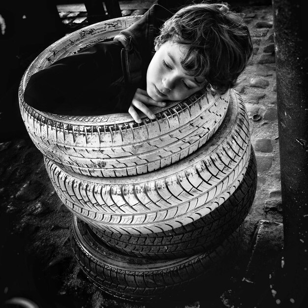 Photo boy sitting in pile of tires