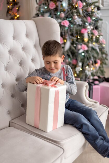 Boy sitting on the sofa and trying to unpack his gift