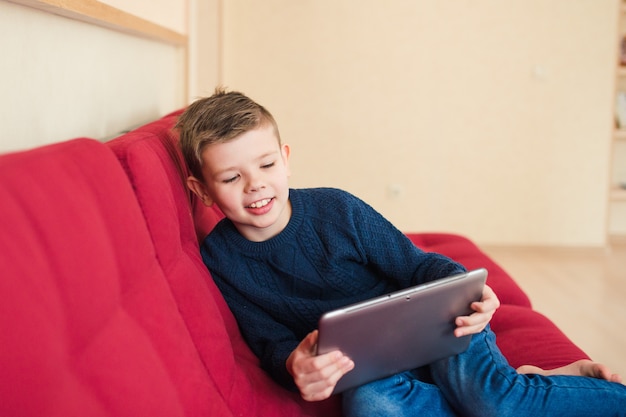 boy sitting on the sofe with tablet