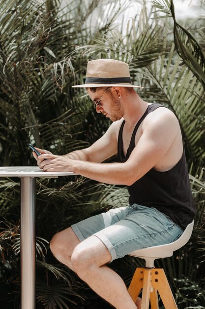 Boy sitting on a stool typing with mobile phone