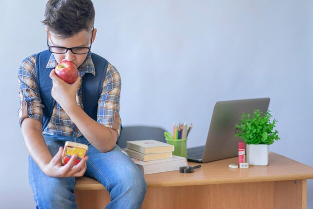 Boy sitting on table while eating an apple photo