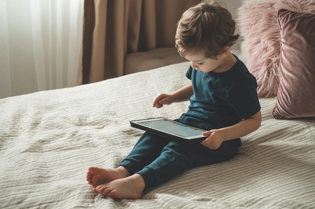 boy sitting with a tablet on the bed