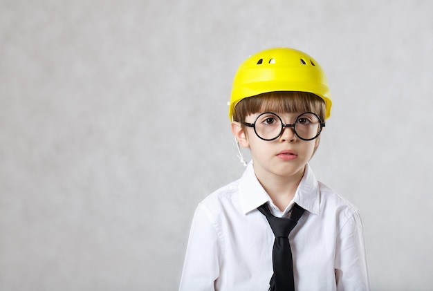 Boy of six years old dressed in white shirt, black tie and protective helmet.