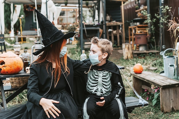 A boy in a skeleton costume and a girl in a witch costume wearing a protective face mask at a Halloween party in a new reality due to the covid pandemic