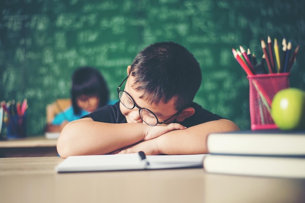 Boy sleeping on the books in the classroom