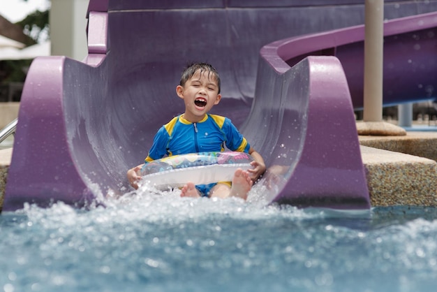 Photo boy sliding down in water slide at water park