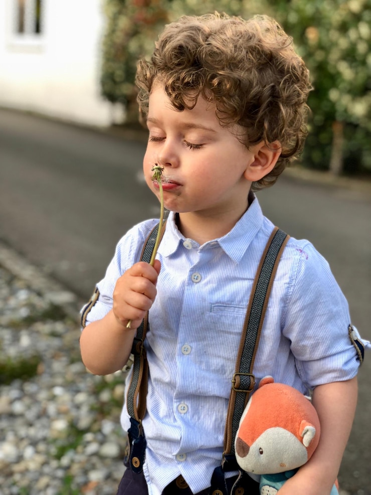 Photo boy smelling dandelion while standing outdoors